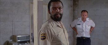 Movie still from “The Island” (1980), directed by Michael Ritchie – A man with a police badge on his chest; Close Up shot, Low angle