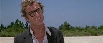 Movie still from “The Island” (1980), directed by Michael Ritchie – A person wearing a suit and glasses; Close Up shot, Low angle