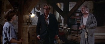 Movie still from “The Island” (1980), directed by Michael Ritchie – A man wearing a suit and tie standing in a room; Wide shot, Low angle