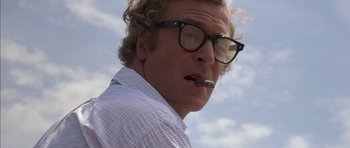 Movie still from “The Island” (1980), directed by Michael Ritchie – A person wearing glasses and smoking a cigarette; Close Up shot, Low angle