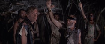 Movie still from “The Island” (1980), directed by Michael Ritchie – A man holding his hand up in the air; Medium shot, Low angle