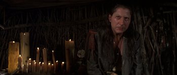 Movie still from “The Island” (1980), directed by Michael Ritchie – A man standing in front of a bunch of lit candles; Close Up shot, Over the shoulder angle