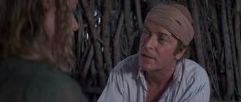 Movie still from “The Island” (1980), directed by Michael Ritchie – A man with a bandage on his head talking to another man; Close Up shot, Over the shoulder angle