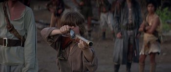 Movie still from “The Island” (1980), directed by Michael Ritchie – A young boy is holding a rifle in his hands; Close Up shot, Over the shoulder angle