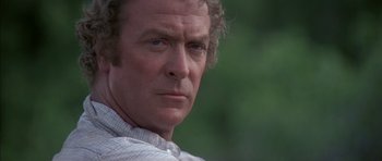 Movie still from “The Island” (1980), directed by Michael Ritchie – A man's face with trees in the background; Close Up shot, Over the shoulder angle