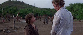 Movie still from “The Island” (1980), directed by Michael Ritchie – A man and a boy are standing in a field; Medium shot, Over the shoulder angle