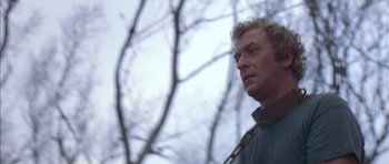 Movie still from “The Island” (1980), directed by Michael Ritchie – A man standing in front of a tree looking to his left; Close Up shot, Low angle