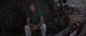 Movie still from “The Island” (1980), directed by Michael Ritchie – A man sitting on a pile of rope in the woods; Medium shot, High angle
