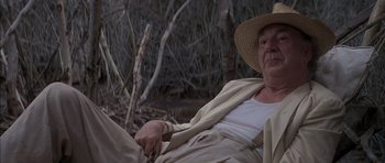 Movie still from “The Island” (1980), directed by Michael Ritchie – An old man wearing a straw hat sitting on a bench; Medium shot, Low angle
