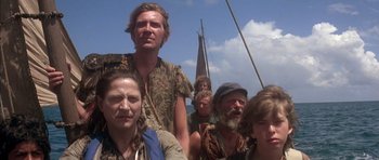 Movie still from “The Island” (1980), directed by Michael Ritchie – A group of people standing next to each other on top of a boat; Medium shot, Low angle