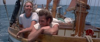Movie still from “The Island” (1980), directed by Michael Ritchie – A man sitting next to another man on a boat; Medium shot, Low angle