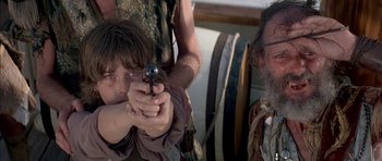 Movie still from “The Island” (1980), directed by Michael Ritchie – A young boy is holding a gun while a older man is holding a gun; Close Up shot, Over the shoulder angle