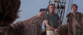 Movie still from “The Island” (1980), directed by Michael Ritchie – A man holding a gun while standing on a boat; Medium shot, Over the shoulder angle