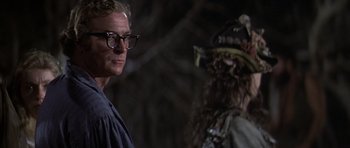 Movie still from “The Island” (1980), directed by Michael Ritchie – A man and a woman wearing glasses in a dark room; Close Up shot, Over the shoulder angle