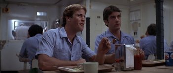 Movie still from “The Island” (1980), directed by Michael Ritchie – Two men sitting at a dinner table eating food; Medium shot, Low angle
