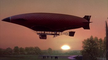 Movie still from “The Island at the Top of the World” (1974), directed by Robert Stevenson – An airship flying over a field with people standing around it; Extreme Wide shot, Low angle