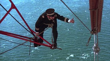 Movie still from “The Island at the Top of the World” (1974), directed by Robert Stevenson – A man in a uniform is on a rope bridge; Wide shot, Overhead angle