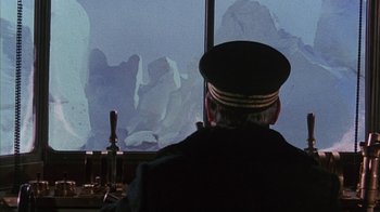 Movie still from “The Island at the Top of the World” (1974), directed by Robert Stevenson – A man wearing a hat sitting in front of a window; Medium shot, Over the shoulder angle