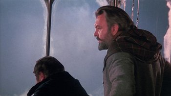 Movie still from “The Island at the Top of the World” (1974), directed by Robert Stevenson – A man with long hair and a goatee is sitting on a bus; Close Up shot, Low angle