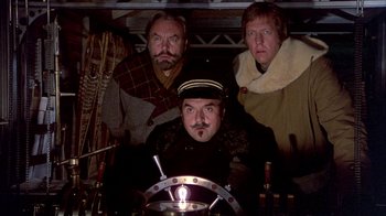 Movie still from “The Island at the Top of the World” (1974), directed by Robert Stevenson – A group of men standing next to each other in a room; Medium shot, Low angle