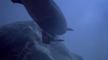 Movie still from “The Island at the Top of the World” (1974), directed by Robert Stevenson – An airship is flying over a snowy mountain; Extreme Wide shot, Low angle