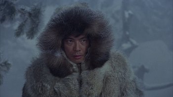 Movie still from “The Island at the Top of the World” (1974), directed by Robert Stevenson – A man wearing a fur coat in the middle of a snowy forest; Medium shot, High angle