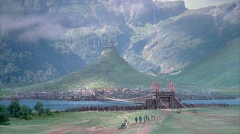 Movie still from “The Island at the Top of the World” (1974), directed by Robert Stevenson – A group of people standing on top of a grass covered field; Extreme Wide shot, High angle