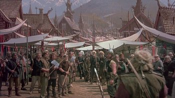 Movie still from “The Island at the Top of the World” (1974), directed by Robert Stevenson – A group of people standing next to each other on a dirt field; Extreme Wide shot, High angle