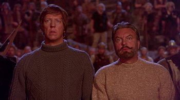 Movie still from “The Island at the Top of the World” (1974), directed by Robert Stevenson – Two men standing next to each other in front of a crowd; Medium shot, Low angle