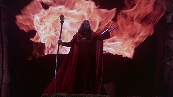 Movie still from “The Island at the Top of the World” (1974), directed by Robert Stevenson – A person in a red robe holding a staff and wearing a red cape; Wide shot, Low angle