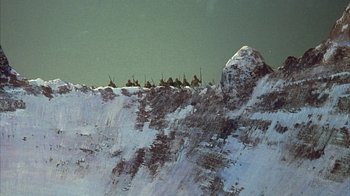 Movie still from “The Island at the Top of the World” (1974), directed by Robert Stevenson – A group of people riding on top of a snow covered hill; Extreme Wide shot, High angle