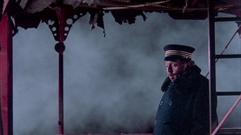 Movie still from “The Island at the Top of the World” (1974), directed by Robert Stevenson – A man in a uniform standing in front of a building; Medium shot, Low angle