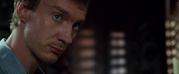 Movie still from “The Island of Dr. Moreau” (1996), directed by Richard Stanley – A man's face in a dark room; Close Up shot, Low angle