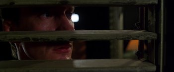 Movie still from “The Island of Dr. Moreau” (1996), directed by Richard Stanley – A man looking through the blinds of a window at night; Extreme Close Up shot, High angle