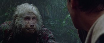 Movie still from “The Island of Dr. Moreau” (1996), directed by Richard Stanley – A man and a monkey in a forest; Close Up shot, Over the shoulder angle