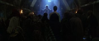 Movie still from “The Island of Dr. Moreau” (1996), directed by Richard Stanley – A group of people standing in a dark room; Wide shot, Over the shoulder angle
