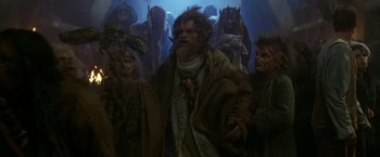Movie still from “The Island of Dr. Moreau” (1996), directed by Richard Stanley – A group of people dressed in costumes in a dark room; Medium shot, High angle
