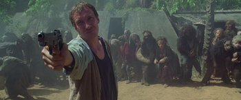 Movie still from “The Island of Dr. Moreau” (1996), directed by Richard Stanley – A man standing in front of a group of people; Medium shot, High angle