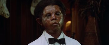 Movie still from “The Island of Dr. Moreau” (1996), directed by Richard Stanley – A man in a white shirt and a black bow tie; Close Up shot, High angle