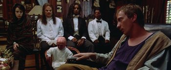 Movie still from “The Island of Dr. Moreau” (1996), directed by Richard Stanley – A group of men sitting in a living room; Medium shot, Low angle