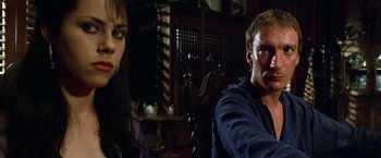 Movie still from “The Island of Dr. Moreau” (1996), directed by Richard Stanley – A man and a woman sitting next to each other in a room; Close Up shot, Low angle