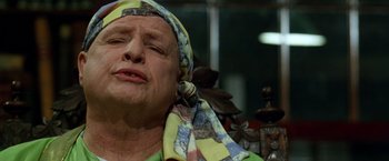 Movie still from “The Island of Dr. Moreau” (1996), directed by Richard Stanley – An older woman wearing a head scarf and a green shirt; Close Up shot, Low angle