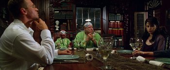 Movie still from “The Island of Dr. Moreau” (1996), directed by Richard Stanley – A group of people sitting at a table with wine glasses; Medium shot, Over the shoulder angle