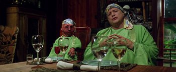 Movie still from “The Island of Dr. Moreau” (1996), directed by Richard Stanley – Two people sitting at a table with wine glasses; Medium shot, High angle