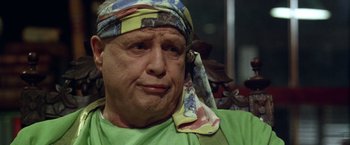 Movie still from “The Island of Dr. Moreau” (1996), directed by Richard Stanley – An older man wearing a head scarf and a green shirt; Close Up shot, Low angle