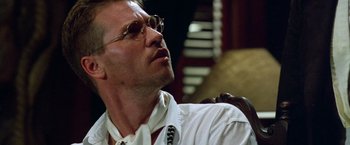 Movie still from “The Island of Dr. Moreau” (1996), directed by Richard Stanley – A person wearing glasses and a white shirt; Close Up shot, Low angle
