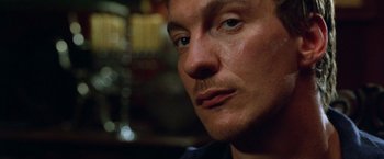 Movie still from “The Island of Dr. Moreau” (1996), directed by Richard Stanley – A man's face in a dark room; Close Up shot, Low angle