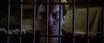 Movie still from “The Island of Dr. Moreau” (1996), directed by Richard Stanley – A person behind a fence; Close Up shot, Low angle