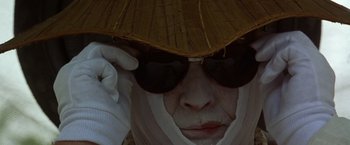 Movie still from “The Island of Dr. Moreau” (1996), directed by Richard Stanley – A person with a hat and sunglasses on; Extreme Close Up shot, Low angle
