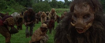 Movie still from “The Island of Dr. Moreau” (1996), directed by Richard Stanley – A group of people dressed like humans in a field; Wide shot, Low angle